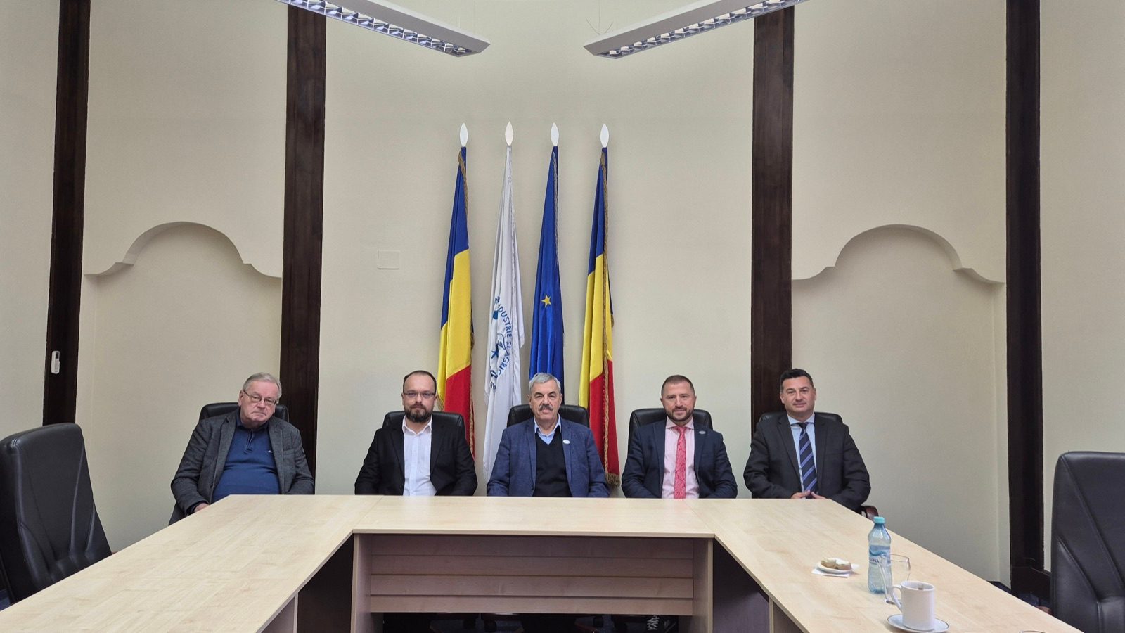 Participants of the inaugural Supervisory Board meeting seated in front of the flags in Arad